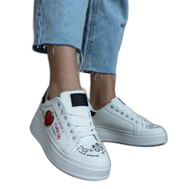 Fehér tornacipő folttal és feliratokkal az emelvényen