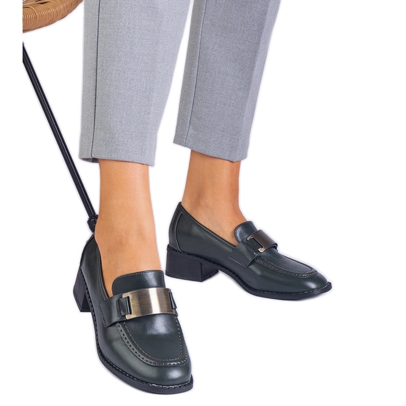 Zöld cipő egy alacsony oszlopon, fémes dekorációval