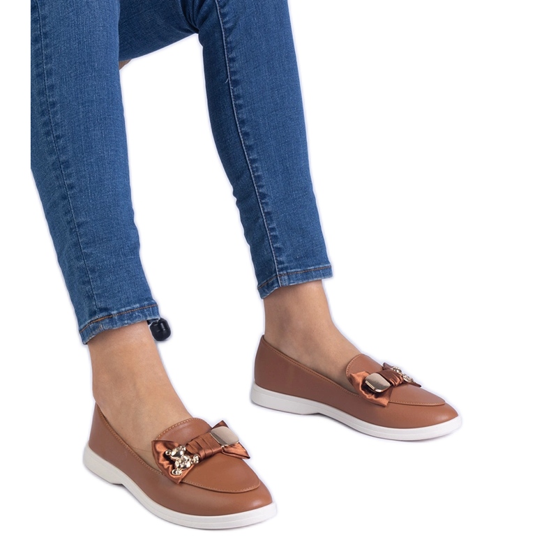 A barna cipők íj és egy arany mackó díszítéssel díszített