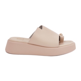 A női papucsok a peronon és az alacsony ékek, dekoratív részletekkel bézs