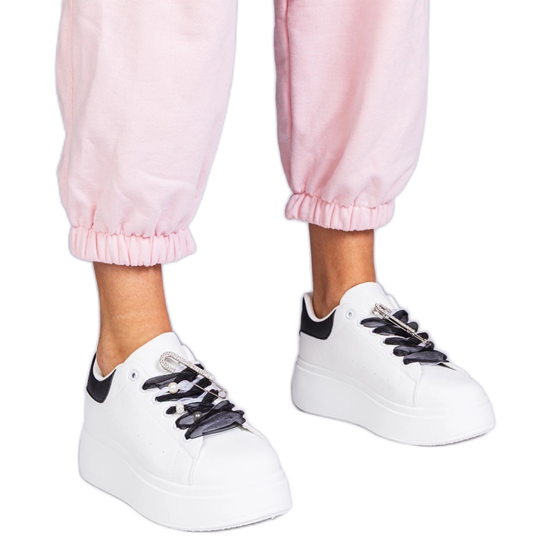 Fehér cipők fekete betéttel és egy cirkonos tűvel