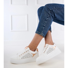 Fehér cipők arany betétekkel a peronon